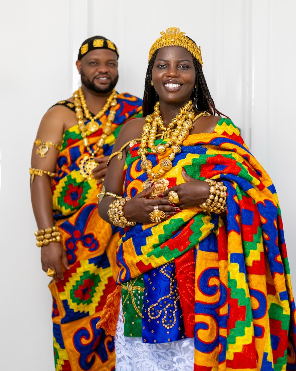 Claudine and Edward posing together in kente and gold regalia